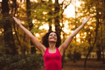 Smiling woman with a arms outstretched in forest — Stock Photo