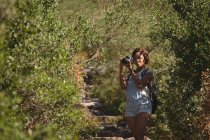 Femme randonneur prenant des photos avec appareil photo numérique dans la forêt à la campagne — Photo de stock