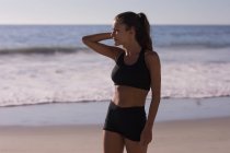 Впишеться жінка в спортивний одяг, стоячи на пляжі в сутінках . — стокове фото