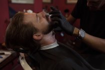 Homme obtenir sa barbe rasée avec tondeuse au salon de coiffure — Photo de stock
