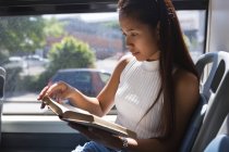 Adolescente lendo um livro no ônibus — Fotografia de Stock