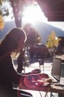 Mulher usando laptop enquanto toma café no café ao ar livre — Fotografia de Stock