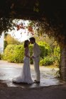 Romantic bride and groom kissing at the garden entrance — Stock Photo
