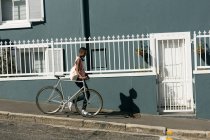 Frau wacht mit Fahrrad auf Bürgersteig in der Stadt auf — Stockfoto