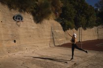 Женщина играет в баскетбол на баскетбольной площадке в солнечный день — стоковое фото