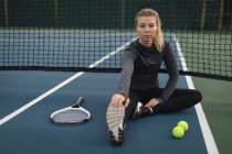 Junge Frau macht Dehnübungen auf dem Tennisplatz — Stockfoto