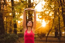 Donna che esegue esercizio di stretching nella foresta in una giornata di sole — Foto stock