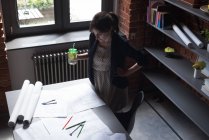 Weibliche Führungskraft arbeitet, während sie im Büro trinkt — Stockfoto