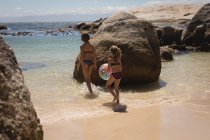 Братья и сестры, гуляющие с мячом в море на пляже — стоковое фото