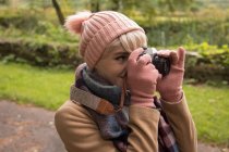 Primo piano della donna che scatta foto con fotocamera vintage nel parco — Foto stock
