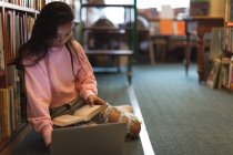 Asian teenage girl using laptop in the library — Stock Photo