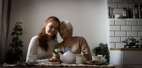 Abuela y nieta interactuando mientras toman el té en casa - foto de stock