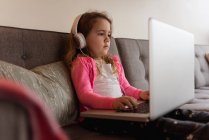 Mädchen benutzt Laptop auf Sofa im Wohnzimmer zu Hause — Stockfoto