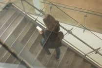 Високий кут зору студента коледжу за допомогою мобільного телефону на сходах — стокове фото