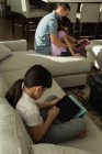 Chica usando tableta digital con su padre en la sala de estar en casa - foto de stock