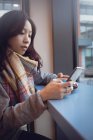 Красива жінка використовує мобільний телефон, маючи каву в кафетерії — стокове фото