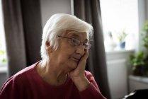 Задумчивая пожилая женщина думает в гостиной дома — стоковое фото