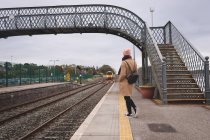 Rückansicht einer Frau, die im Bahnhof auf Zug wartet — Stockfoto