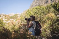 Femme randonneur prenant des photos avec appareil photo numérique dans la forêt à la campagne — Photo de stock