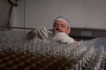 Trabalhador masculino colocando garrafas vazias em rack na fábrica — Fotografia de Stock