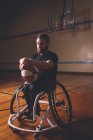 Homme handicapé réfléchi tenant le basket-ball dans la cour — Photo de stock