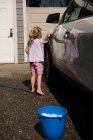Fille laver une voiture au garage extérieur par une journée ensoleillée — Photo de stock