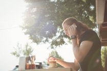 Homme parlant sur téléphone portable tout en prenant un café au café extérieur — Photo de stock