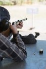 Rear view pf man aiming shotgun at target in shooting range — Stock Photo