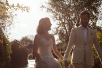 Happy Bride and groom walking hand in hand in the garden — Stock Photo