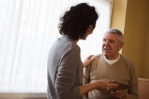 Cuidador mostrando tableta digital a la mujer mayor en el hogar de ancianos - foto de stock