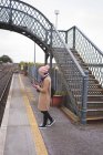 Вид збоку жінки з використанням мобільного телефону на залізничній платформі — стокове фото