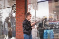 Красива дівчина використовує мобільний телефон, маючи каву за межами торгового центру — стокове фото