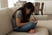 Menina usando telefone celular na sala de estar em casa — Fotografia de Stock
