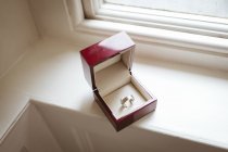 Alto angolo di anello d'oro in scatola tenuto sul davanzale della finestra — Foto stock