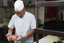 Jefe de cocina sosteniendo plato de sushi en la cocina en restauant - foto de stock