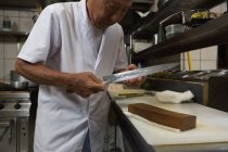 Старший шеф-повар держит нож на кухне в отеле — стоковое фото