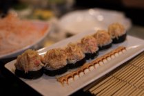 Sushi servido em um prato com molho guarnecido em um restaurante — Fotografia de Stock