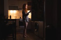 Femme ouvrant un réfrigérateur à la maison — Photo de stock