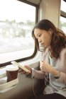 Жінка використовує мобільний телефон, слухаючи музику на мобільному телефоні в потязі — стокове фото