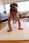 Маленькая девочка делает отжимания в гостиной дома — стоковое фото