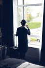 Vista posteriore della donna che parla sul cellulare in camera d'albergo — Foto stock
