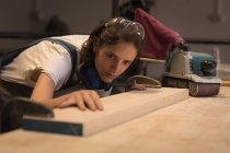 Young craftswoman examining board in workshop. — Stock Photo