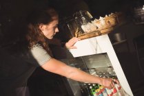 Kellner arrangiert Flasche im Kühlschrank — Stockfoto