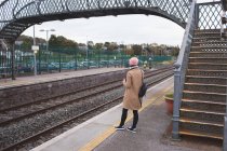 Вид ззаду жінки, що стоїть на залізничній станції — стокове фото
