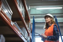 Женщина-работница ведет учет цифровых планшетов на фабричном складе — стоковое фото