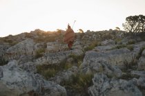 Вид сзади на человека масаи в традиционной одежде, идущего по скале в сельской местности — стоковое фото