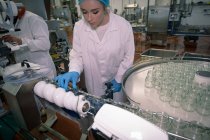 Lavoratrice che monitora i vasi di vetro sulla linea di produzione in fabbrica — Foto stock