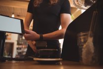 Клиент делает оплату с умными часами на прилавке в кафетерии — стоковое фото