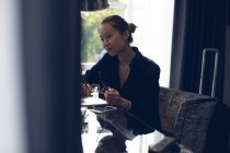 Продумана жінка сидить з окулярами за столом в готелі — стокове фото