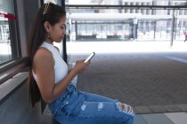 Adolescente usando telefone celular na parada de ônibus — Fotografia de Stock